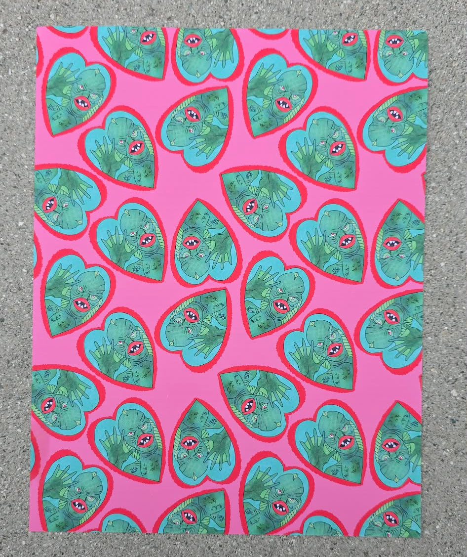 Patterned paper with green heart shapes on a pink background, placed on a textured surface.