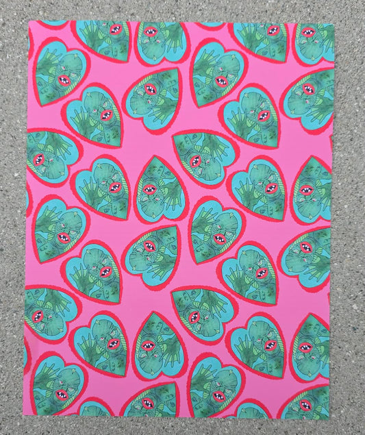 Patterned paper with green heart shapes on a pink background, placed on a textured surface.