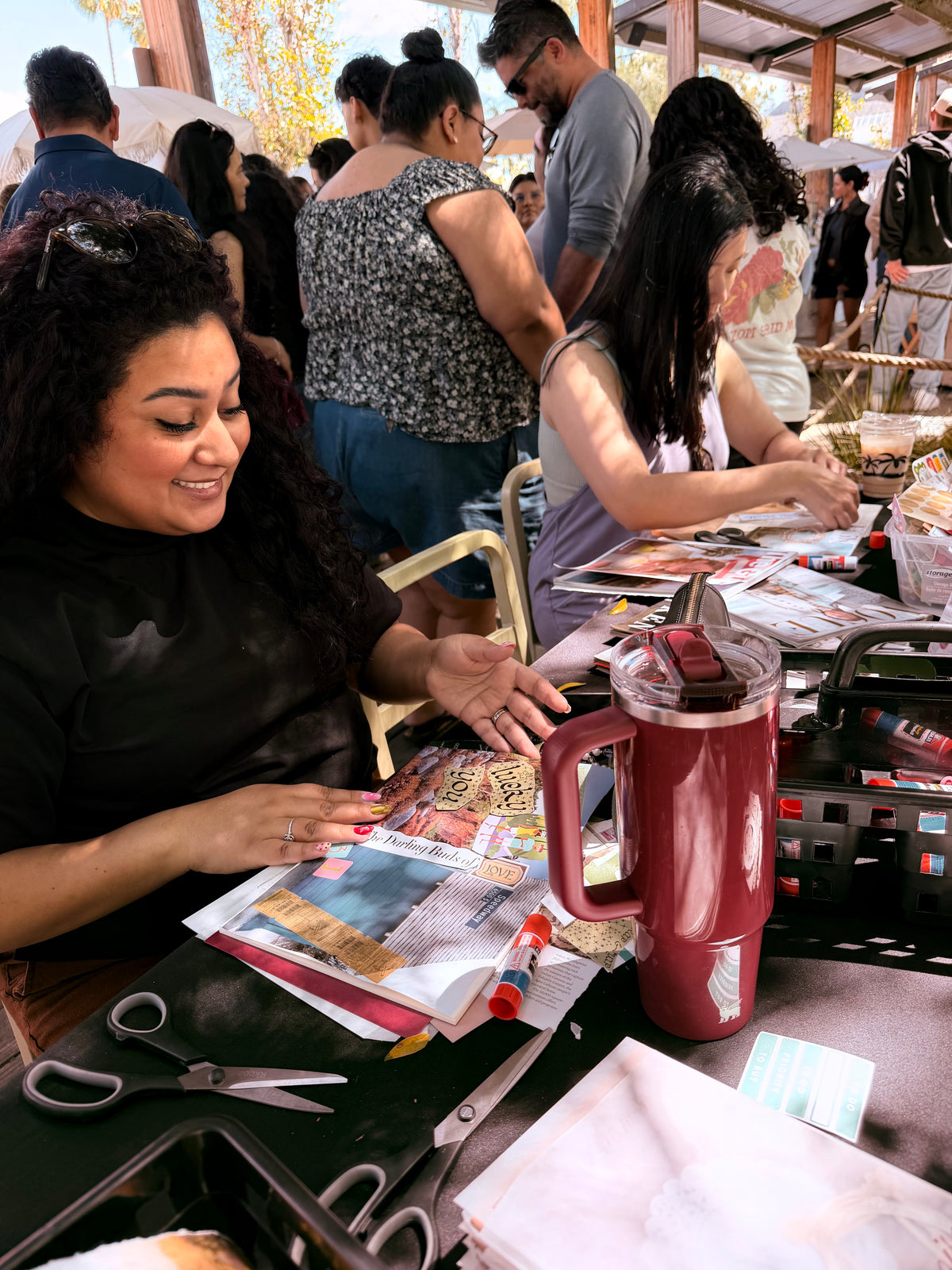 Woman working on a craft project at a table with various materials and a red pitcher.